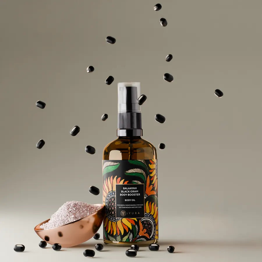 Black gram lentils falling beside a copper bowl and the bottle